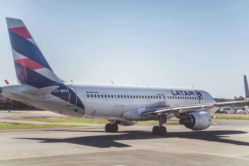 A LATAM Airlines Airbus A320 preparing for takeoff on a sunny airport runway.